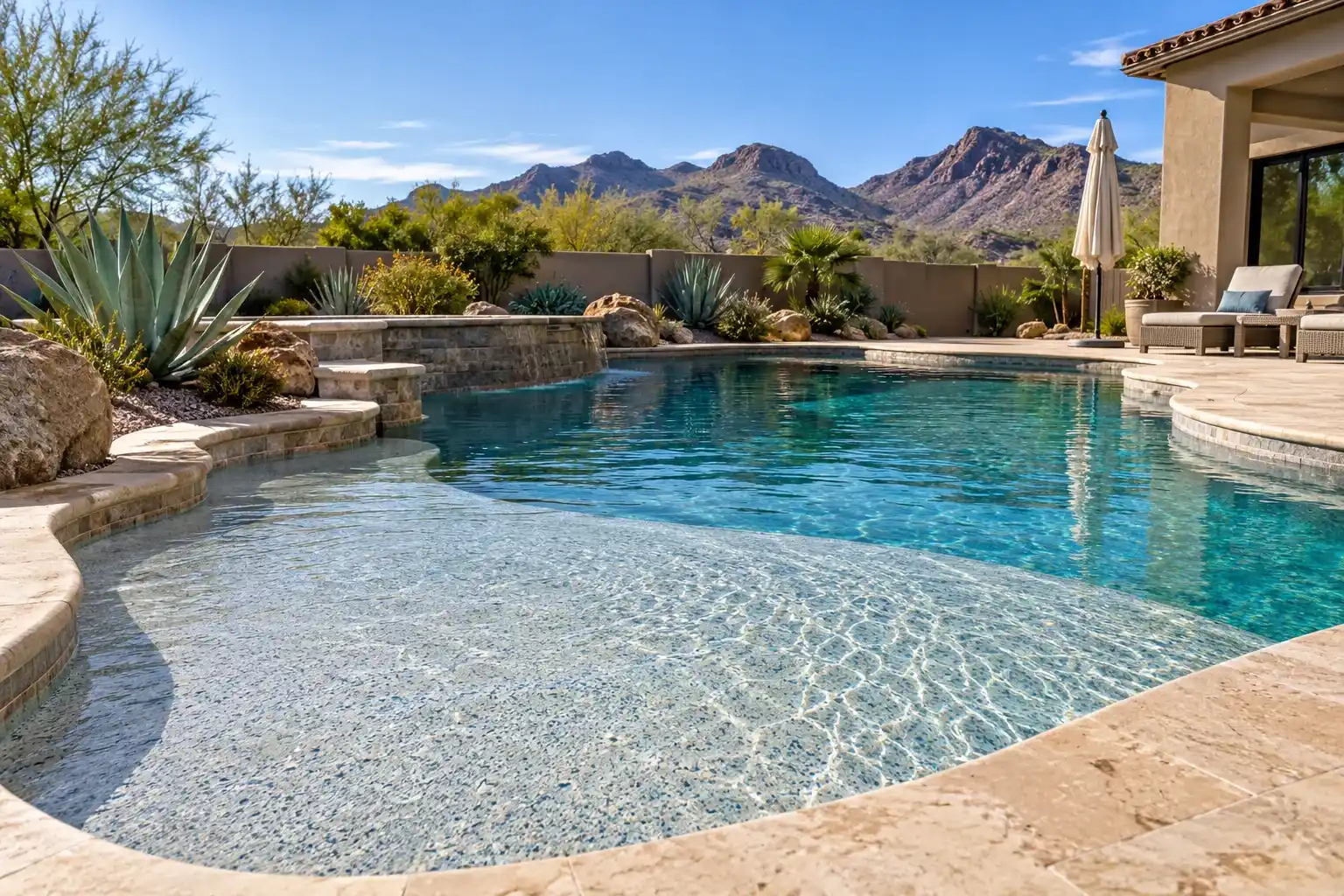 Pool with a wide shallow tanning shelf and a pale blue aggregate finish, mountains behind