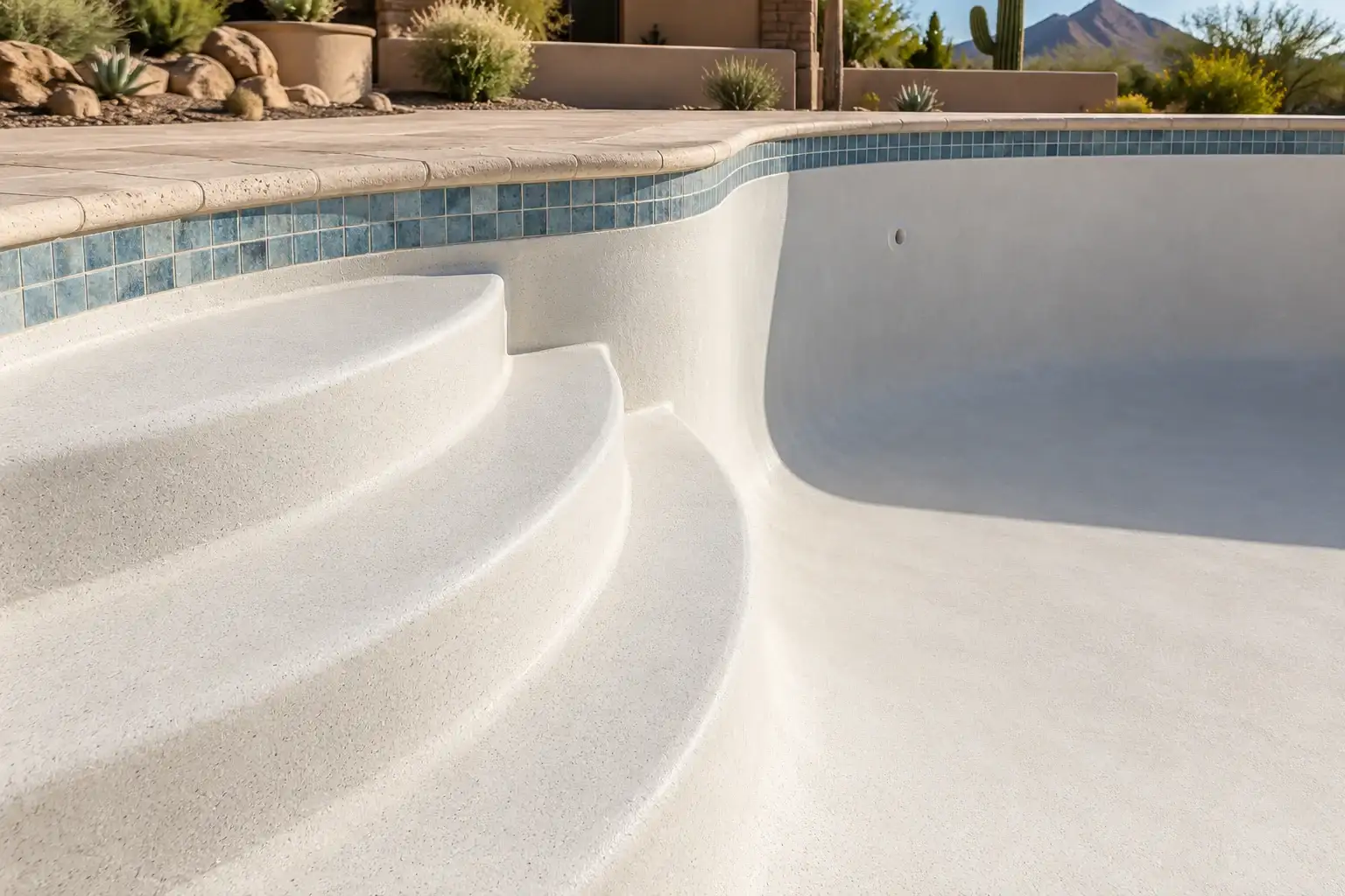 Curved entry steps with a smooth ivory quartz finish in an empty pool