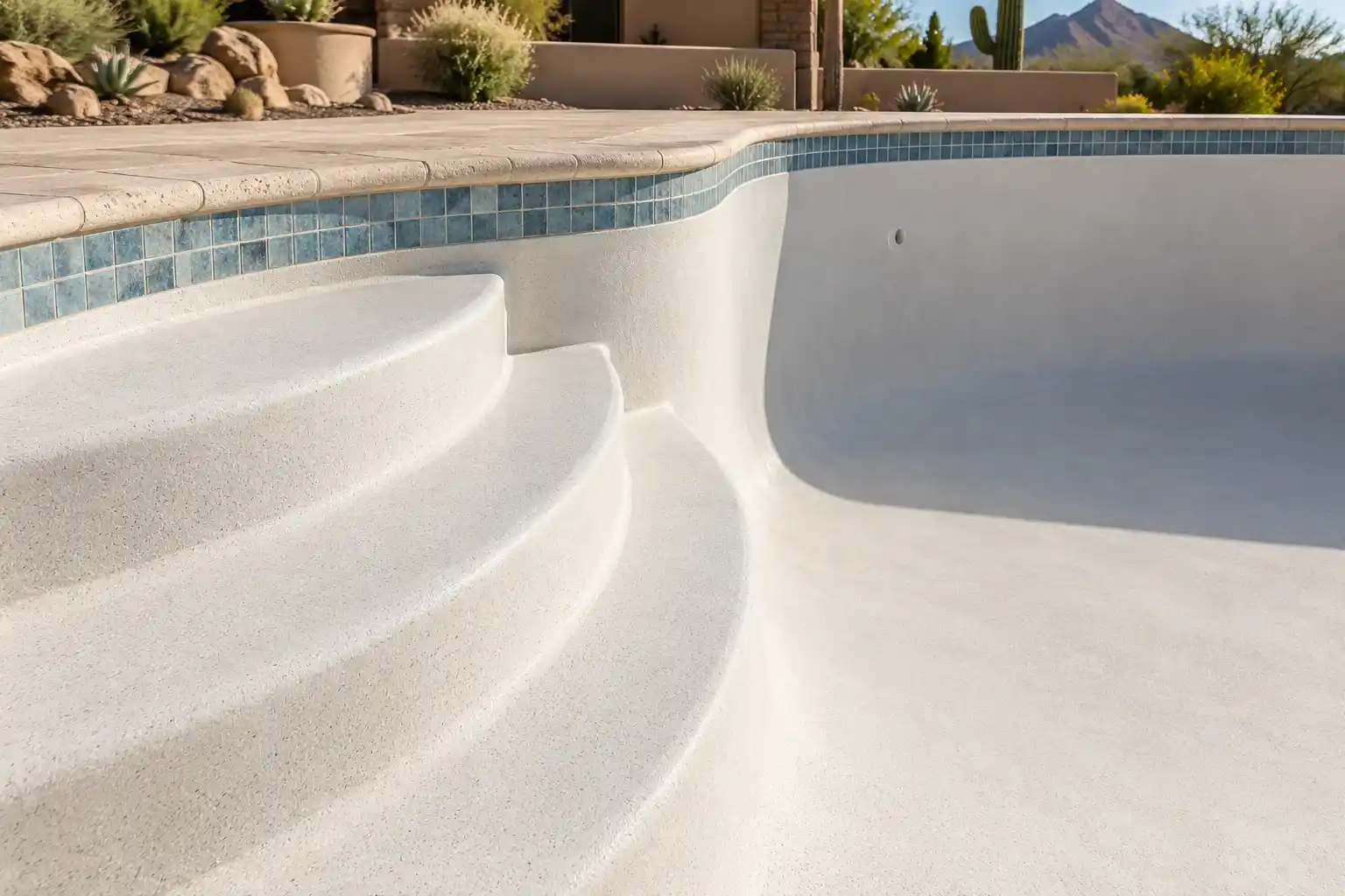 Curved entry steps with a smooth ivory quartz finish in an empty pool